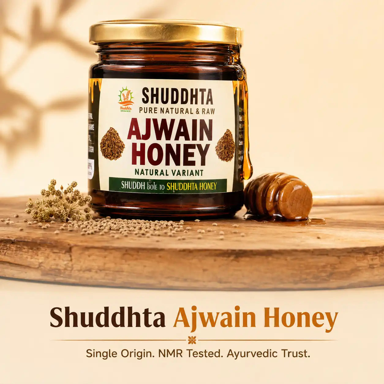 A jar of Shuddhta Ajwain Honey displayed on a wooden board with a honey dipper and loose seeds, set against a warm beige background with text overlays at the bottom.