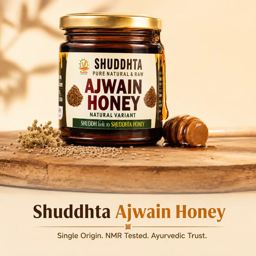 A jar of Shuddhta Ajwain Honey displayed on a wooden board with a honey dipper and loose seeds, set against a warm beige background with text overlays at the bottom.