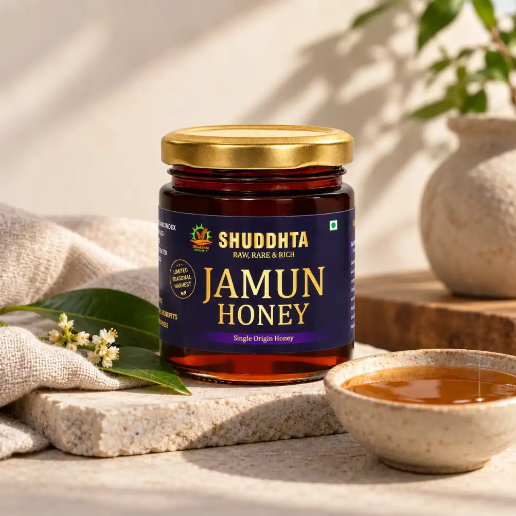 Shuddhta Jamun Honey jar on a stone slab with a bowl of honey and green leaves in warm sunlight