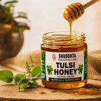 A jar of Shuddhta Tulsi Honey with honey dripping from a wooden dipper, set on a rustic wooden surface with fresh tulsi leaves and a soft, warm background.