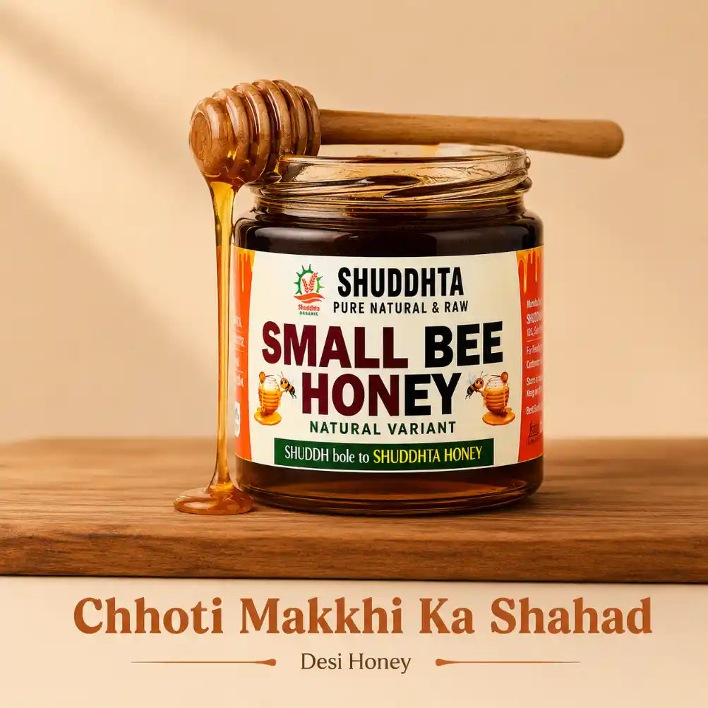 A jar of Shuddhta Small Bee Honey sits on a wooden surface with honey dripping from a wooden honey dipper. The background is a warm beige with soft shadows, and text below reads 'Chhoti Makkhi Ka Shahad' and 'Desi Honey'.